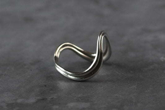 Certified London Hallmarked .925 Sterling Silver wave ring with a unique looped design, resting on a textured dark grey surface.
