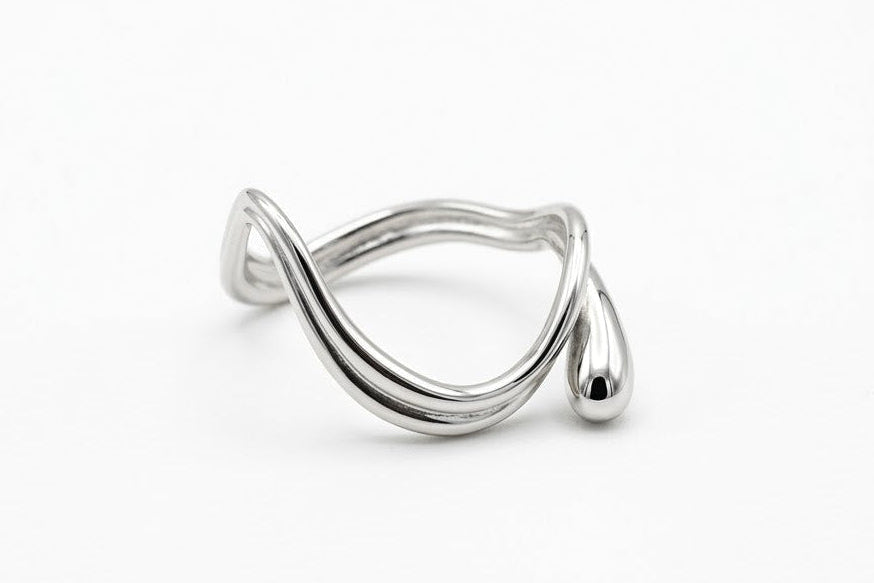 A polished silver wrap ring with a wavy, fluid design and a small teardrop accent, photographed on a seamless white background.