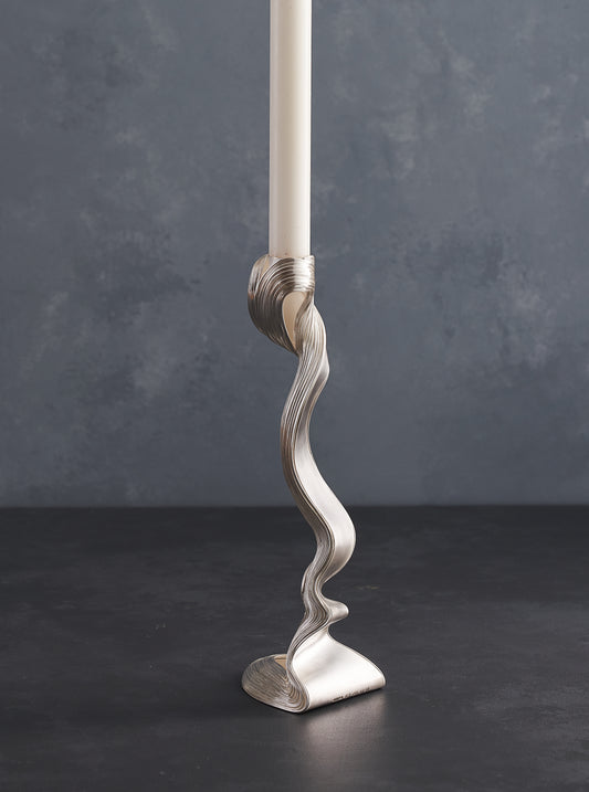 A Pair of silver candlesticks with white candles on the table 